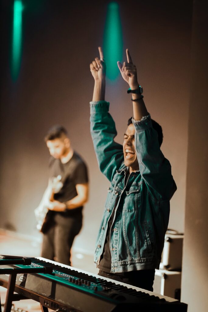 Musician points towards the heavens as turquoise light shines down.