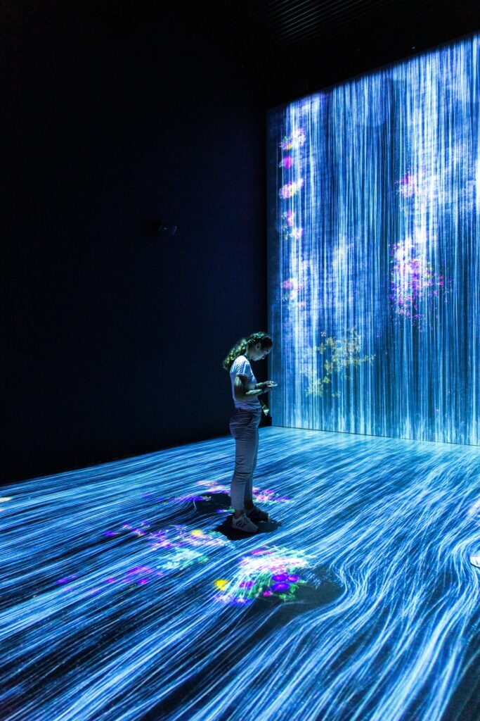 individual interacting with mobile device, surrounded by trails of blue light symbolizing digital information.